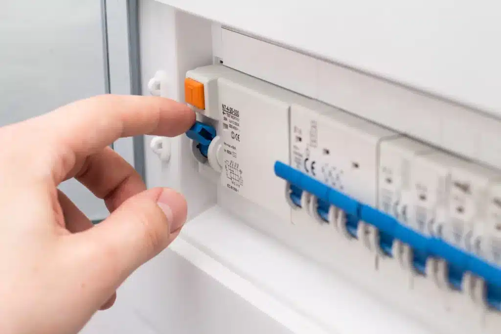 A hand checking the tripping breaker circuit for AC fuse