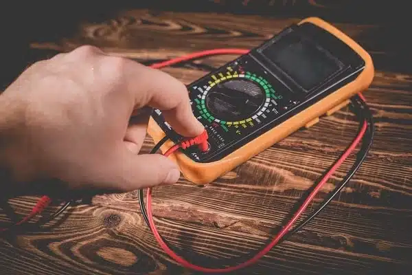 A person checking the AC fuse with a multimeter