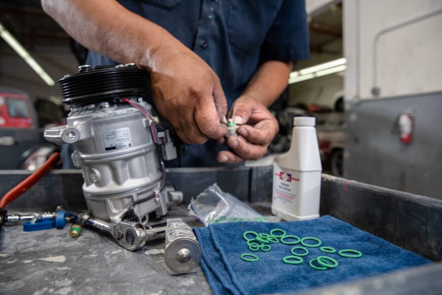 A person fixing an AC Compressor