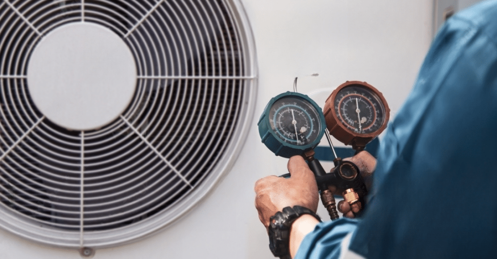 A person holding a pressue meter guage infront of an AC compressor