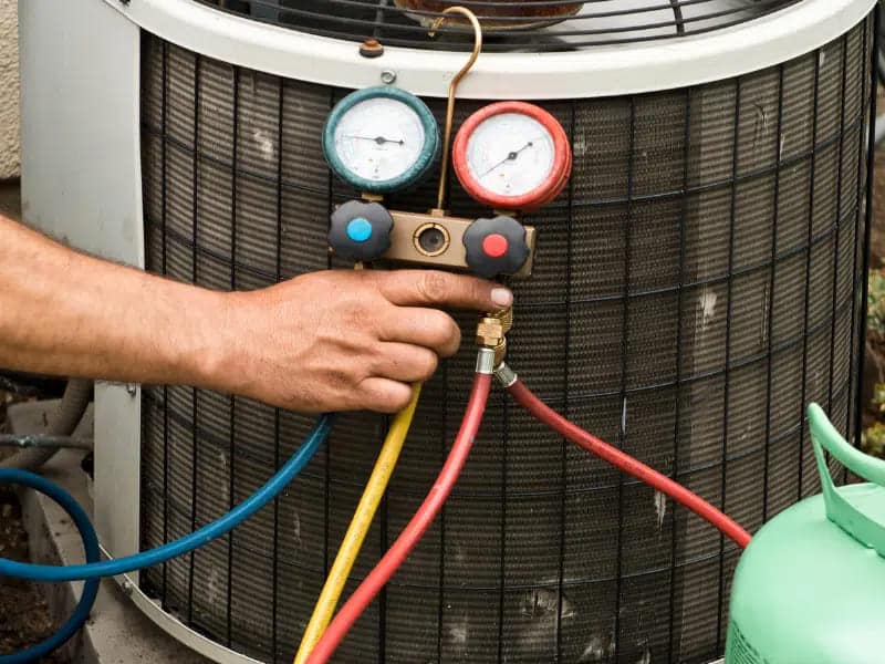 A person holding the meter for an AC refrigerant