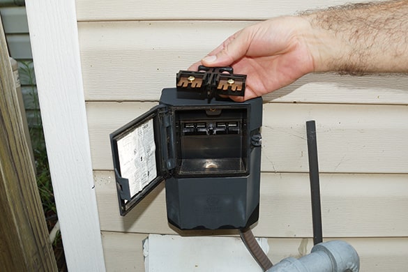 A person touching an opened AC fuse box empty on the inside