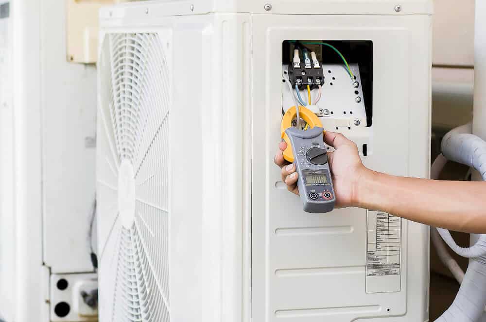 A view of a hand checking the AC fuse with a plier