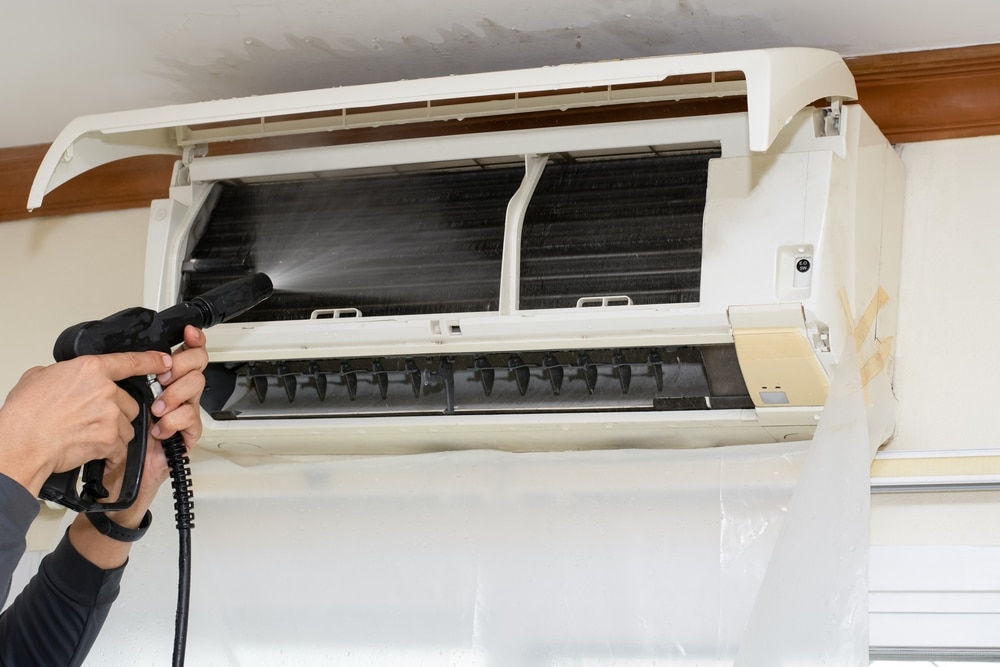 A view of a person cleaning an ac coil with water pressure