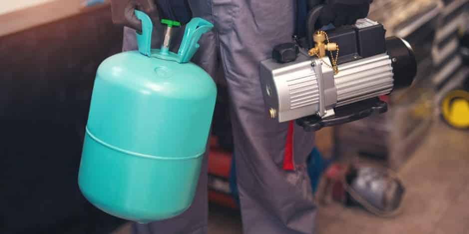 A view of a person holding a Freon and AC compressor