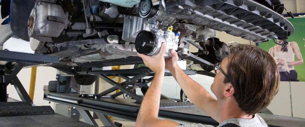 A view of a person removing the AC compressor