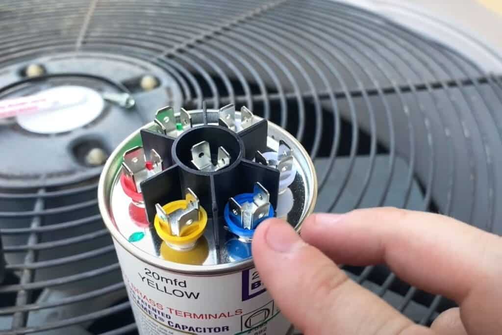 A view of a person touching the opened AC capacitor