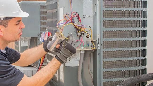 A view of a technician dealing with wires and attaching an AC capacitor