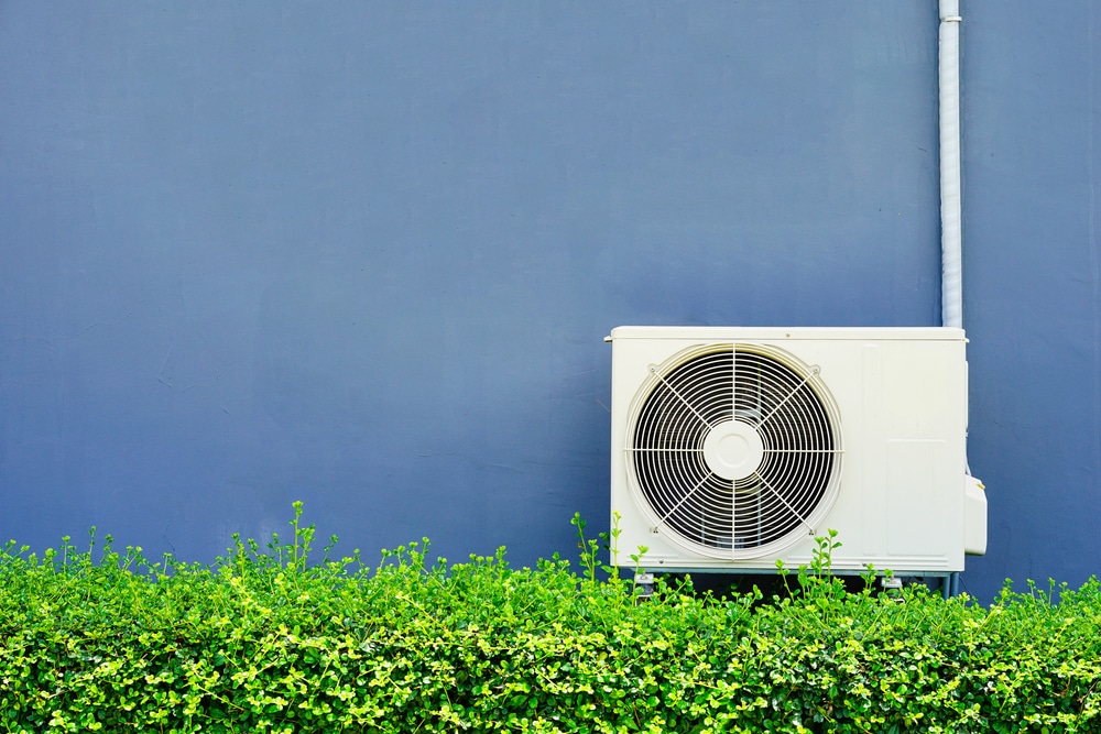 A view of an AC outer in a garden by a blue wall