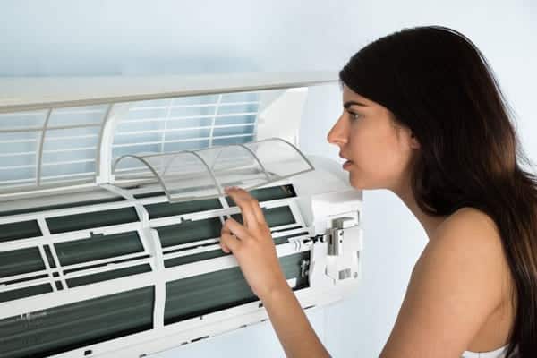 a women is checking the ac after hearing whistling sounds from AC