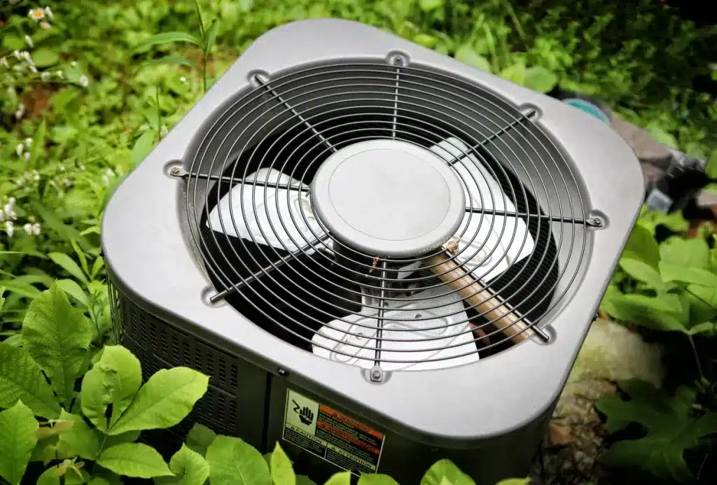 A close view of an ac fan in between leafy garden