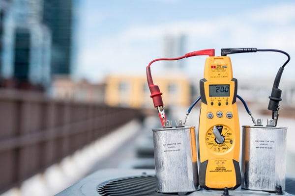 A view of a dual ac capacitor being tested with a multimeter