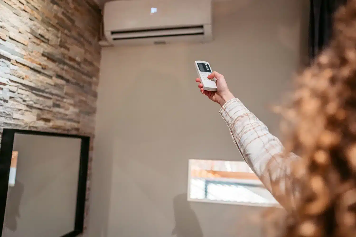 A view of a lady adjusting an ac temperature with a remote