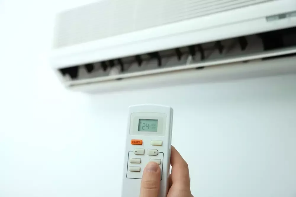 A view of a person holding an ac remote to an ac