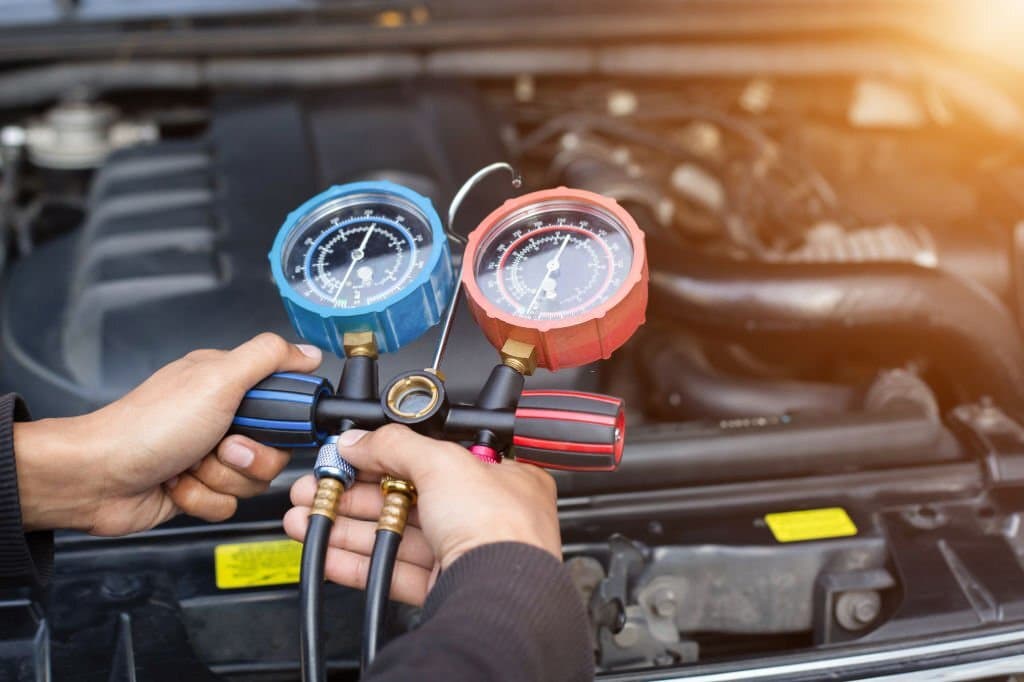 A view of a person checking the air conditioner pressure inside a car engine