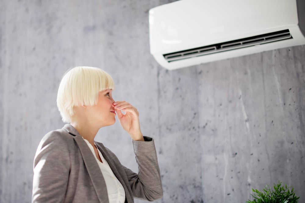 A view of a woman covering her nose due to the bad ac smell