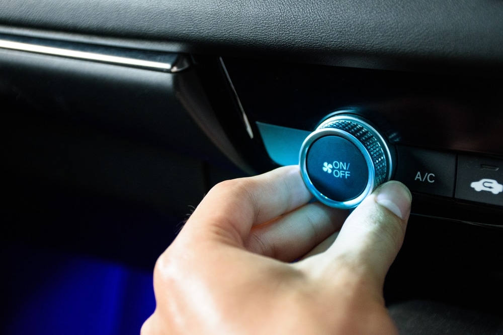 A view of a person switching on the car ac button